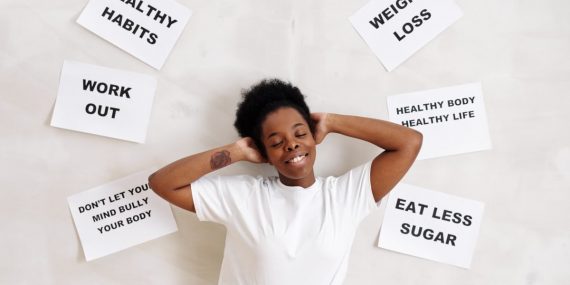 Smiling woman embracing positive lifestyle with healthy living messages around her.